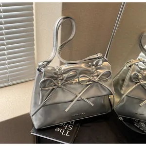Detail of silver metallic tote bag showing bow decoration and ruched texture with metal logo