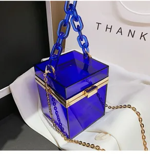 Detail view of royal blue acrylic box bag with gold metal trim and chunky chain handle