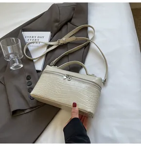 Dettaglio borsa beige a scatola con stampa coccodrillo, zip d'argento e tracolla sottile