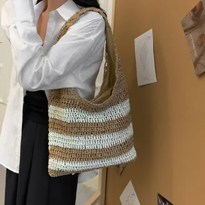 Close-up of a large capacity striped straw tote bag worn over the shoulder by a model