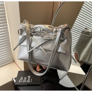 Detail of silver tote bag featuring chic double bow design and pleated metallic texture
