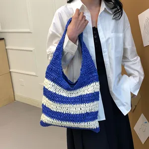 Detailed texture of blue and beige striped straw tote bag with wide shoulder strap