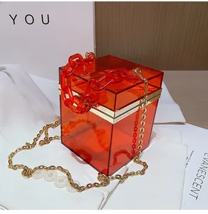 Macro detail of orange transparent acrylic handbag with chunky chain and gold frame