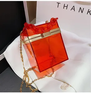 Detail of red acrylic square handbag with gold metal frame and thick chain handle