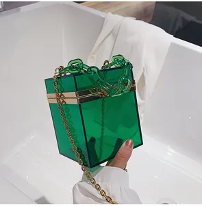 Detail of emerald green acrylic box bag with gold metal frame and thick chain handle