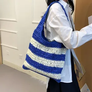 Detail of blue and white striped woven straw tote bag showing texture and shoulder strap