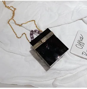 Close-up of black acrylic box clutch with purple resin chain and gold metal strap