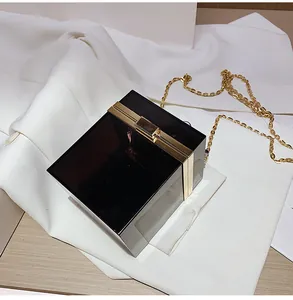 Detail view of square acrylic box bag with gold metal frame and chain strap