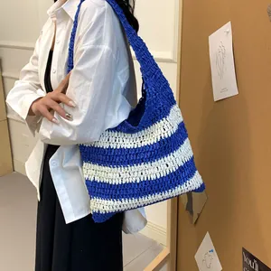 Detail of blue and white striped straw woven tote bag showing texture and strap