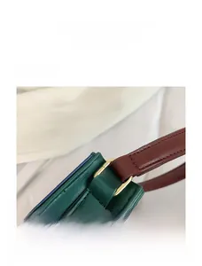 Détail du sac en cuir vert vintage avec boucles dorées et bandoulières rouge-brun