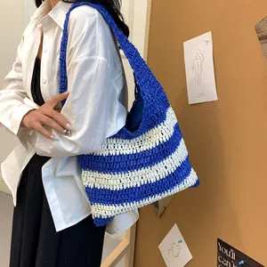 Detail of the blue and white striped woven tote bag shown on a model for beach vacation