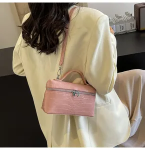 Dettaglio borsa rosa con trama a coccodrillo e doppie cerniere in metallo argentato