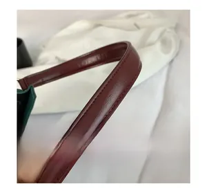 Gros plan détaillé de la bandoulière en cuir bordeaux avec texture et coutures