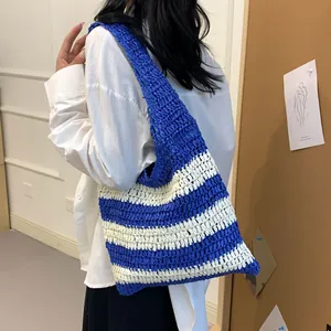 Close-up of blue and white striped straw woven hobo bag carried by a model