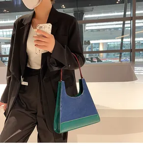 Détail d'un sac à main vintage bicolore bleu et vert en cuir avec anse fine rouge