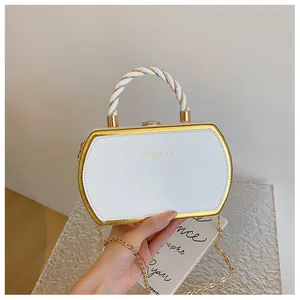 Nahaufnahme der weißen Abendtasche mit Goldrahmen und geflochtenem Griffdesign