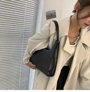Vue latérale d'un sac sous les aisselles en cuir noir vintage porté sur un manteau blanc