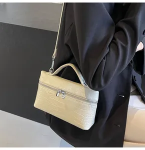 Dettaglio borsa beige chiaro motivo coccodrillo con cerniere argento e tracolla sottile