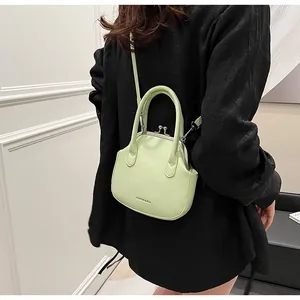Detail showing the light green shell bag with vintage metal clasp and PU leather texture