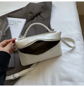Dettaglio mini borsa bianca a motivo coccodrillo con zip argentata e tracolla regolabile