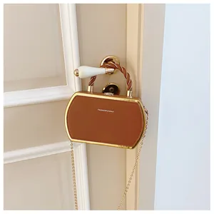 Detailansicht der braunen Leder-Box-Tasche mit Goldrahmen am weißen Türgriff