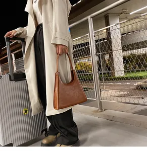 Détail d'un sac à bandoulière marron en similicuir dans un décor de voyage tendance