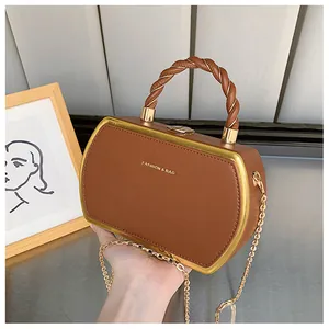 Detailansicht der dunkelbraunen Handtasche mit geflochtenem Griff und Goldkette