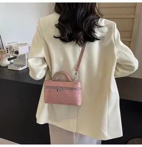 Borsa a mano da donna rosa con motivo a coccodrillo, indossata da una modella in blazer