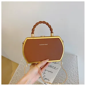 Detail einer braunen Ledertasche mit goldenem sechseckigem Metallrahmen und Kette