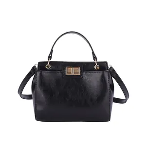 Chic black faux leather handbag with golden rectangular twist lock and adjustable strap
