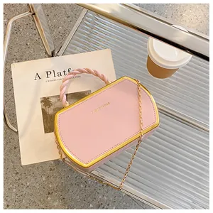 Detailaufnahme einer rosa Koffer-Handtasche mit Goldrand und Kettenriemen