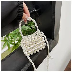 Detailopname van de handgemaakte witte mini-pareltas met elegante parelgreep en riem
