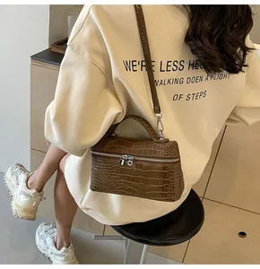 Mini borsa a mano marrone testurizzata a coccodrillo indossata a tracolla da una modella