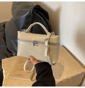 Dettaglio borsa a mano beige effetto coccodrillo con finiture in argento