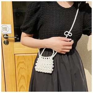 Detail van handgemaakte parel crossbody tas met strikdecoratie op een zwarte getextureerde mouw