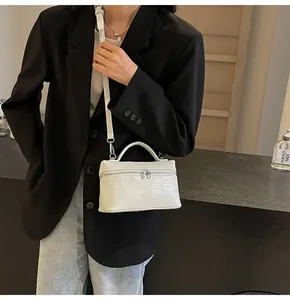 Dettaglio di una borsa bianca a trama coccodrillo con chiusura in metallo argentato