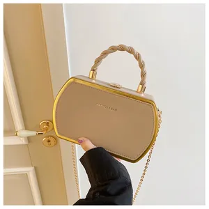 Details einer beige hexagonalen Tasche mit geflochtenem Rundgriff und Goldkette