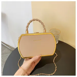 Detail der beigen sechseckigen Box-Tasche mit Goldrahmen und geflochtenem Griff