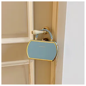 Nahaufnahme einer hellblauen Umhängetasche mit Goldverzierung an einer Türklinke hängend