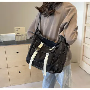 Detail of black canvas messenger bag with white straps and buckle on a casual outfit