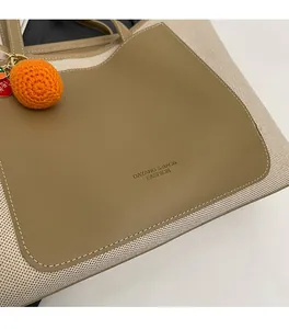 Close-up of canvas tote bag stitching with leather logo and knitted persimmon charm