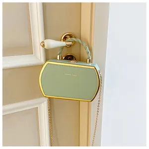 Details einer minzgrünen Koffer-Tasche mit Goldrand an einem weißen Türgriff