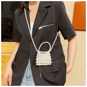 Detail van handgemaakte mini-crossbodytas van witte parels met handvat en lange parelketting