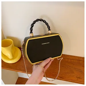 Details einer schwarzen geometrischen Handtasche mit Goldbeschlägen und Kettenriemen