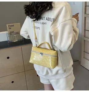 Dettaglio della borsa gialla a motivo coccodrillo con zip in argento e tracolla sottile