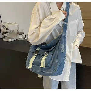 Detail of light blue denim messenger bag with double buckles and distressed texture