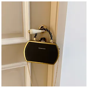 Detail einer schwarzen Box-Tasche mit Goldrahmen und Modeschriftzug an der Tür