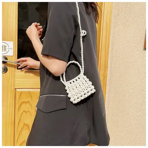 Detailweergave van de handgemaakte witte parel mini crossbody tas op een model