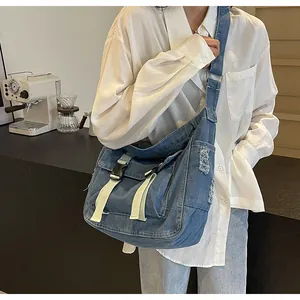 Detailed view of blue denim messenger bag with flap buckle and frayed edge texture