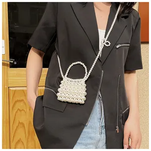 Detailweergave van een handgemaakte witte parel mini tas met parelstrik en lange riem